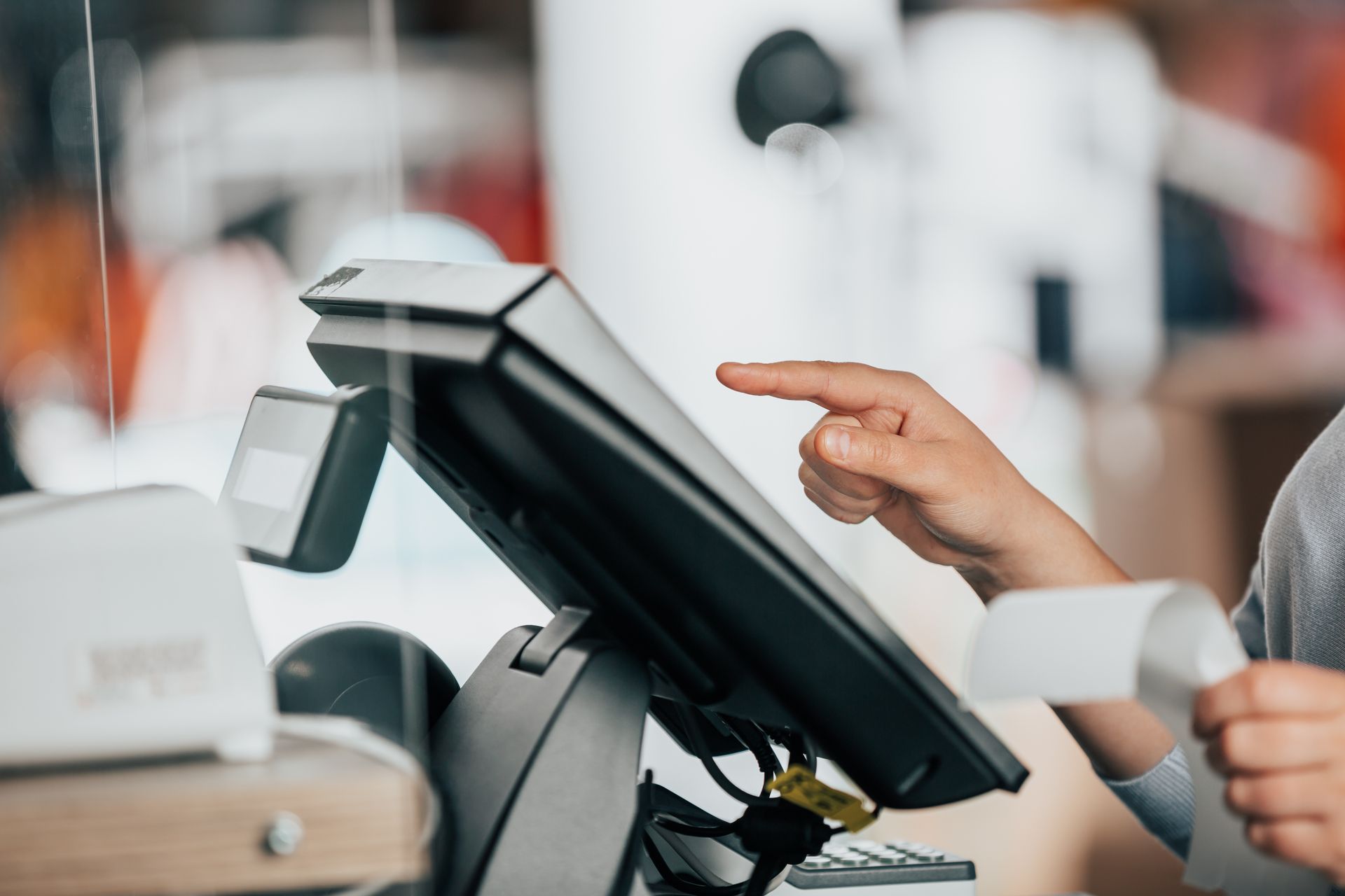 Customer taps a retail touchscreen checkout terminal while holding a card reader in a store. Customer taps a retail touchscreen checkout terminal while holding a card reader in a store.