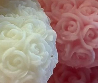 Drie kleine, met bloemen bedekte teddyberen in rood, wit en roze op een tafel met hartvormige versieringen.