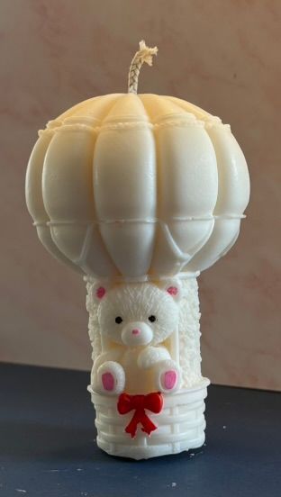 Klein decoratief wit kaarsje in de vorm van een heteluchtballon met een klein beertje in het mandje.