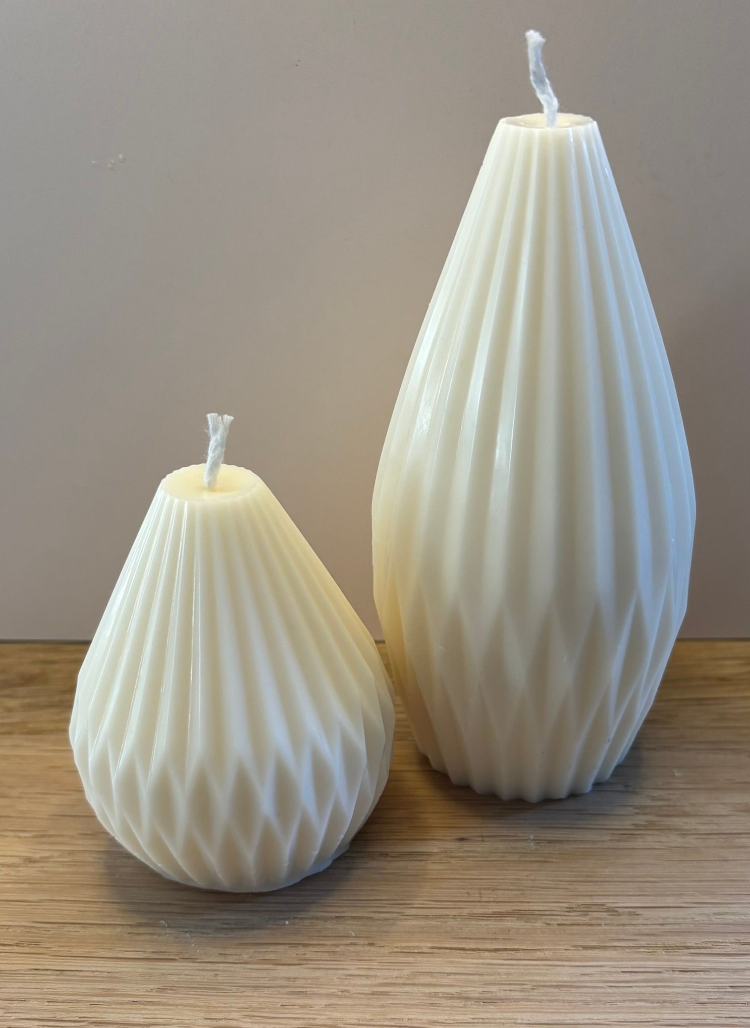 Twee handgemaakte Cone Pillar kaarsen van sojawas in ivoorwit, verkrijgbaar in Small en Large, met een elegant geribbeld design.