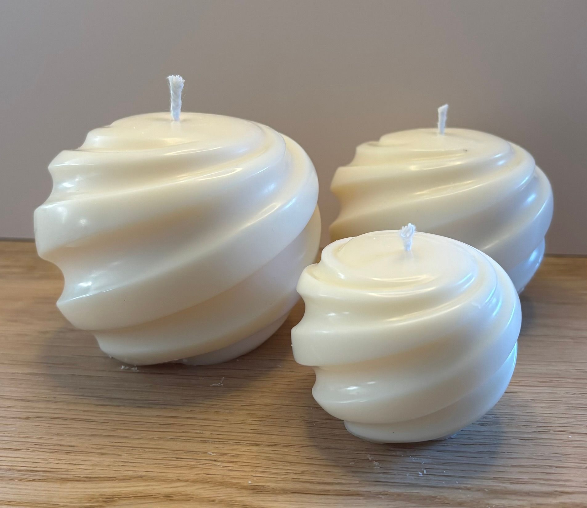 Drie handgemaakte Swirl Pillar kaarsen van ivoorwitte sojawas in Small, Medium en Large met een elegant gedraaid design.