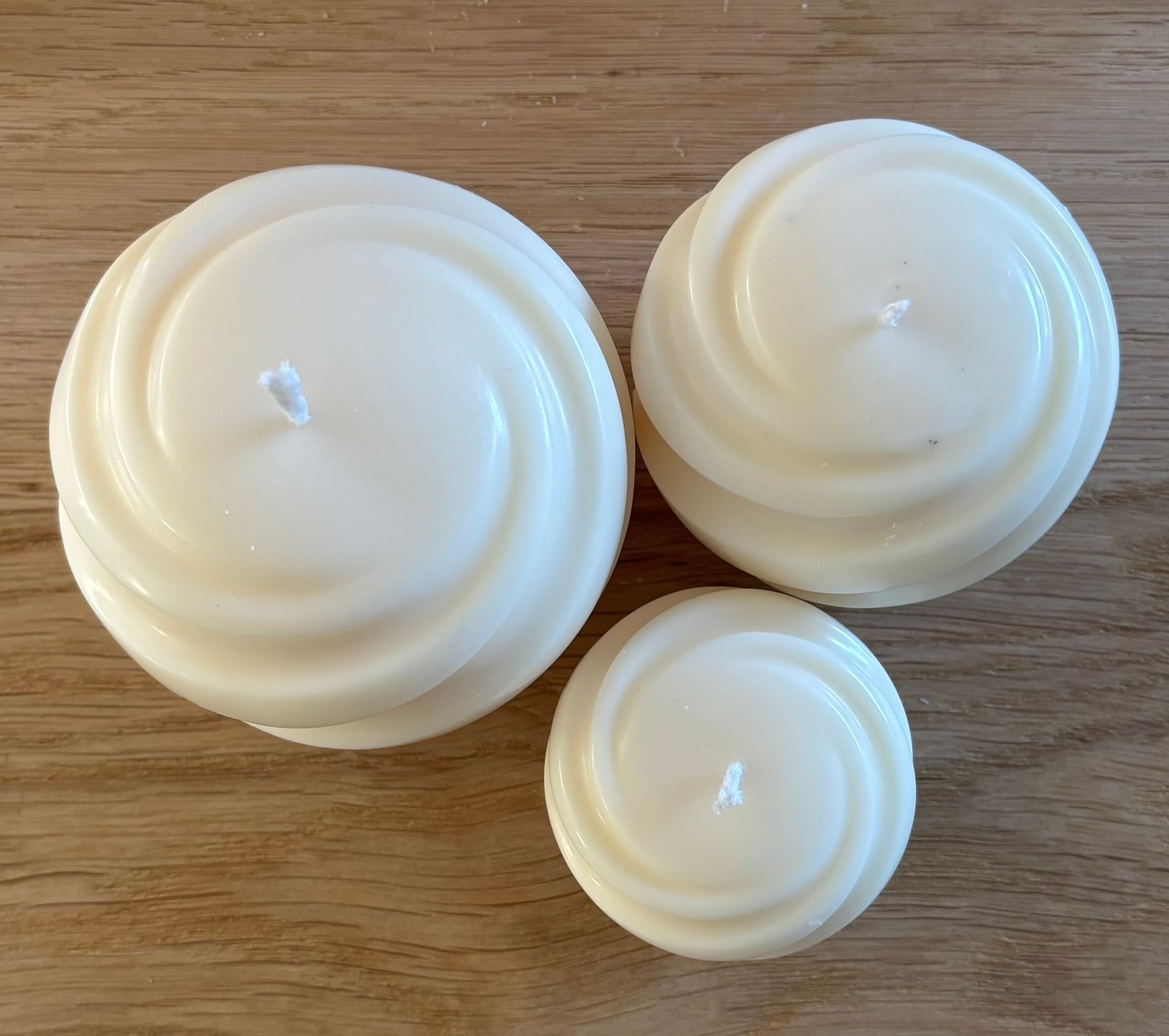 Drie handgemaakte Swirl Pillar kaarsen van ivoorwitte sojawas in Small, Medium en Large met een elegant gedraaid design.