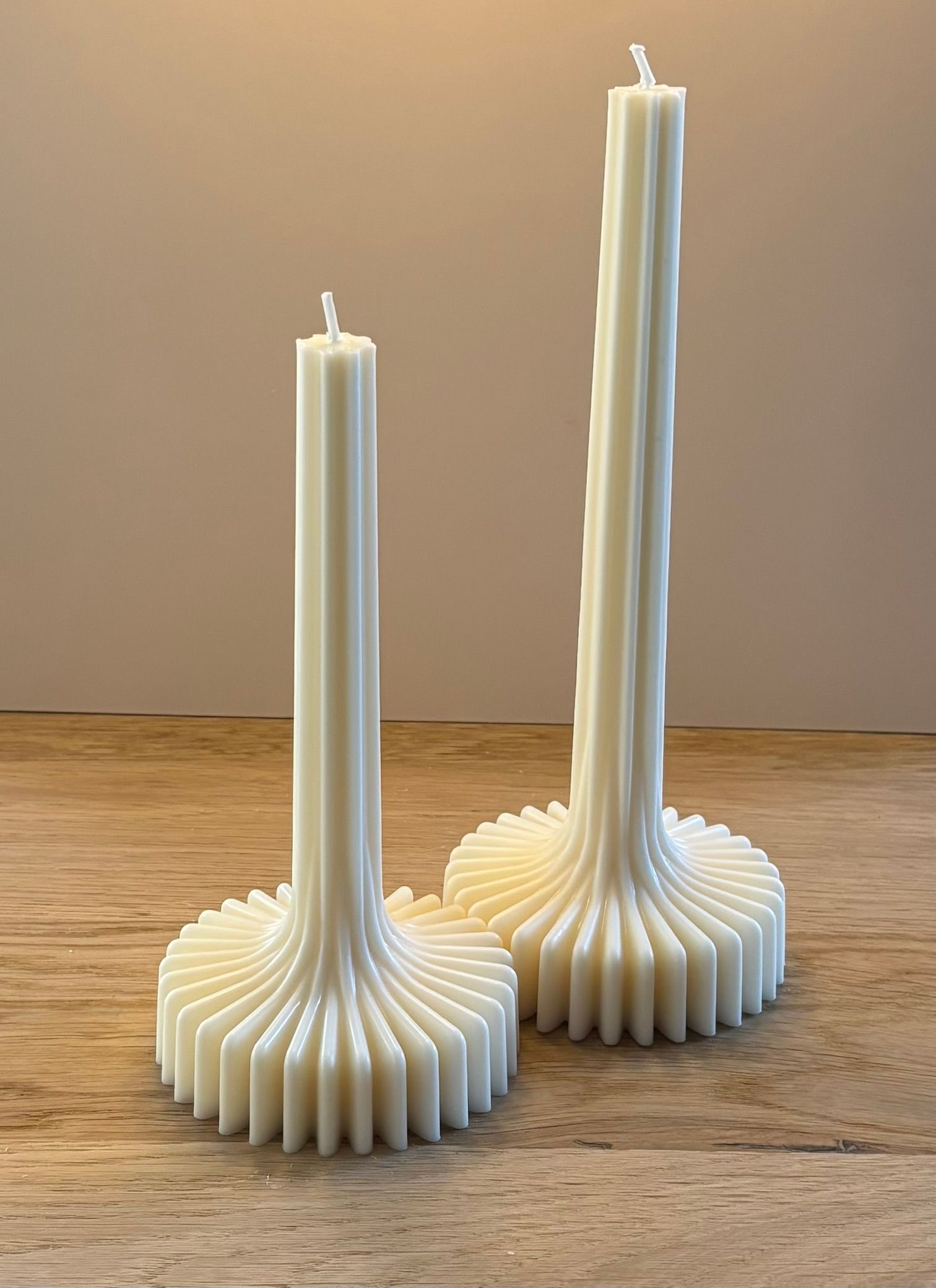 Twee witte sculptuurkaarsen met bloemachtige voet