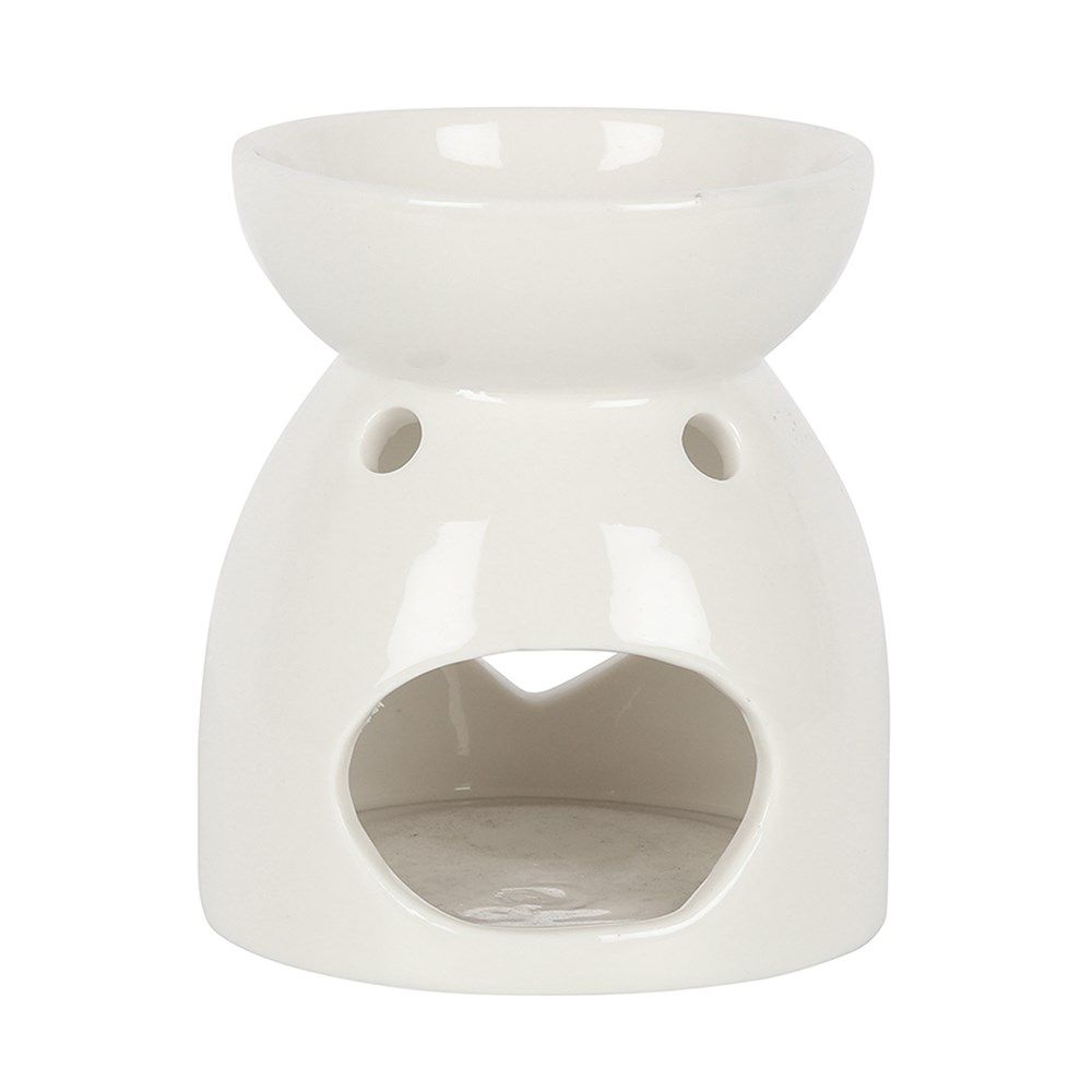 Een witte keramische waxbrander met een hartvormige uitsparing, een brandend theelichtje erin en kleine paarse waxblokjes op een tafeltje.