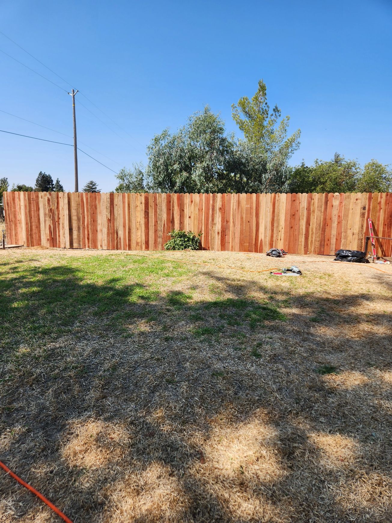 A wooden fence is being built in a backyard.