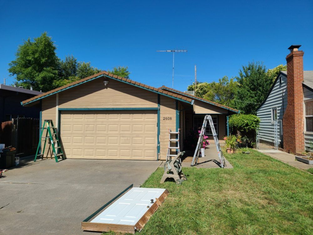 A house with a garage door and a ladder in front of it