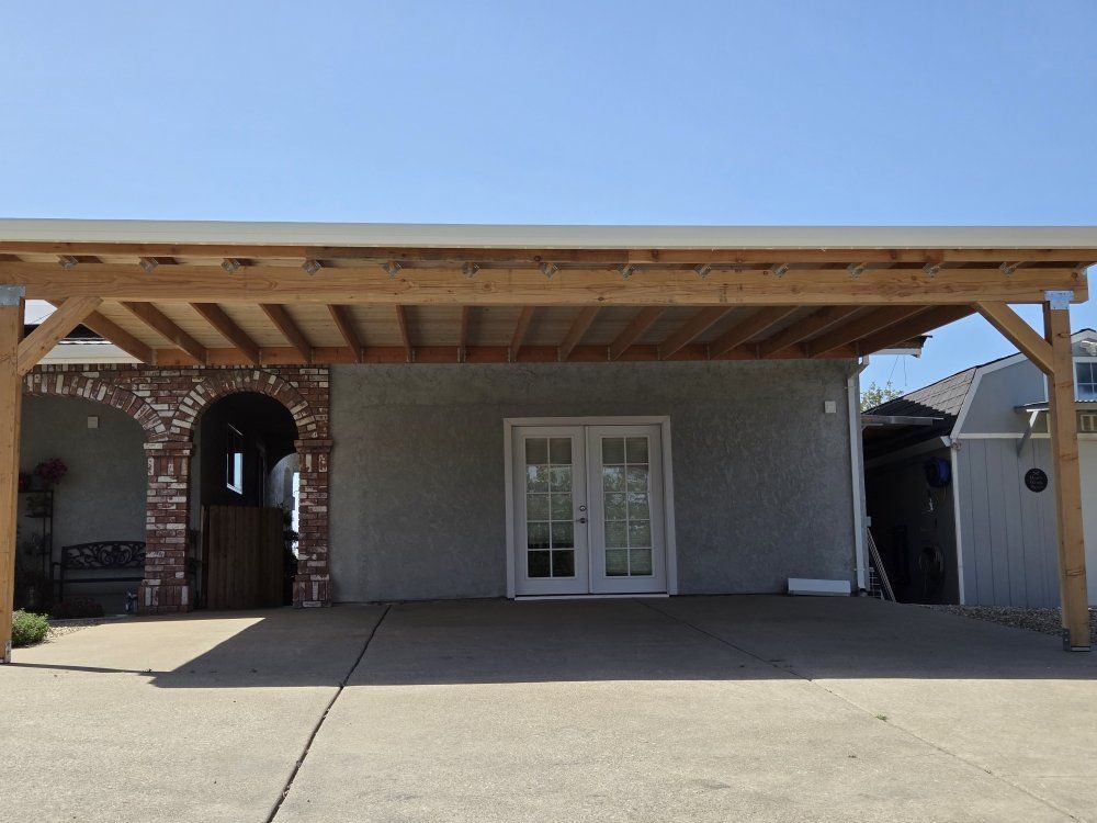 A carport with a wooden roof in front of a house