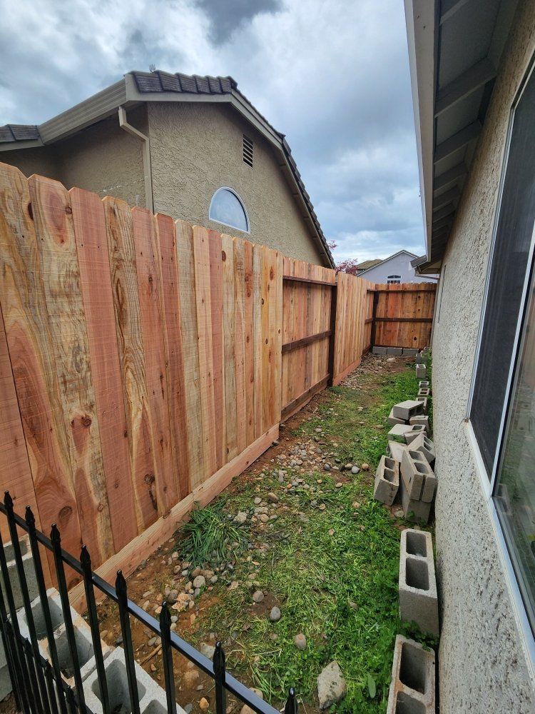 A wooden fence is in the backyard of a house.