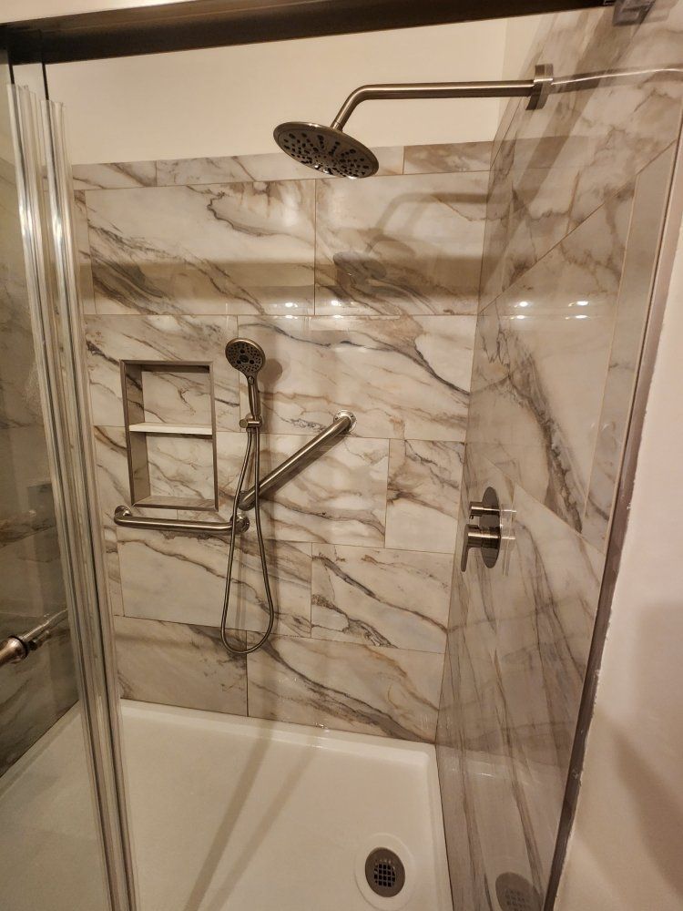 A shower with a sliding glass door and a shower head.