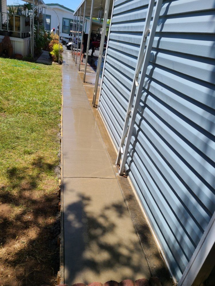 A sidewalk leading to a house with a fence in the background.