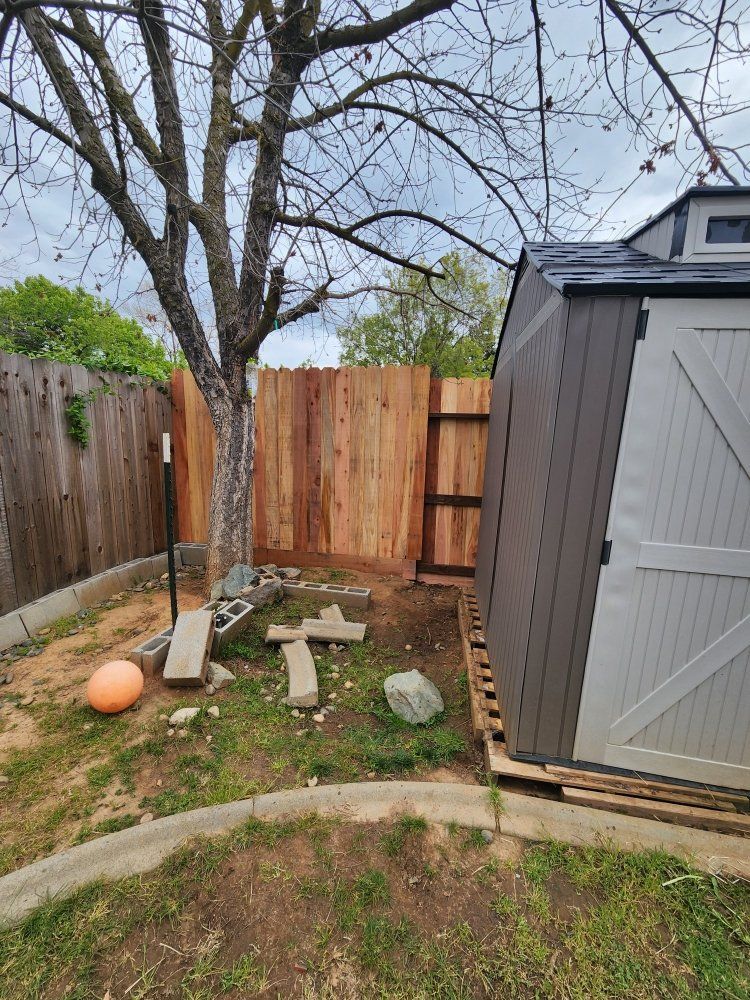 A backyard with a shed and a wooden fence.