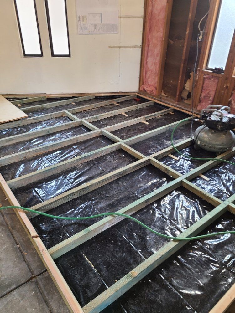 A person is working on a wooden floor in a room.
