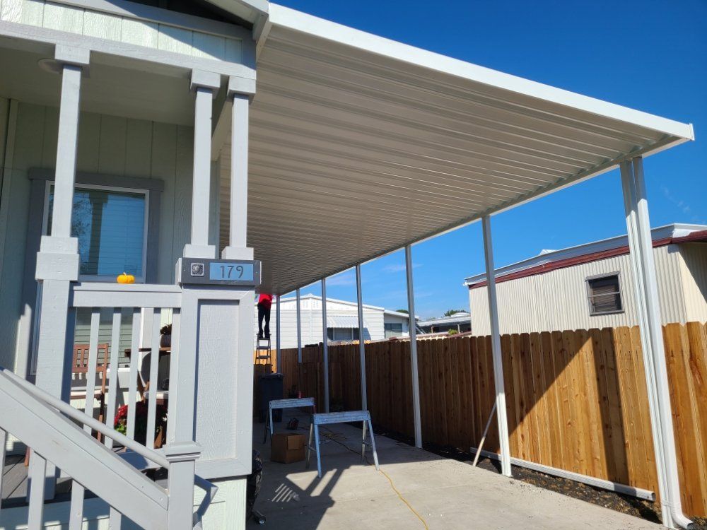 A mobile home with a covered porch and a wooden fence.