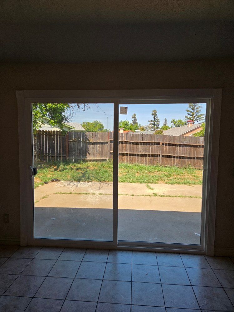 An empty room with a sliding glass door leading to a backyard.