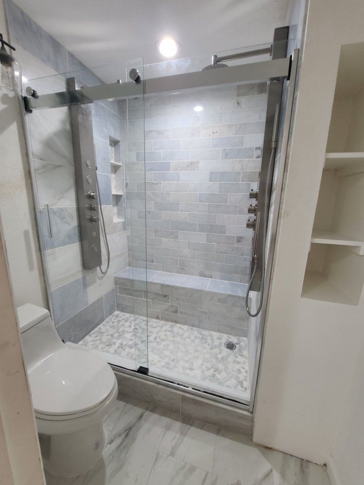 A bathroom with a toilet , shower , and mirror.