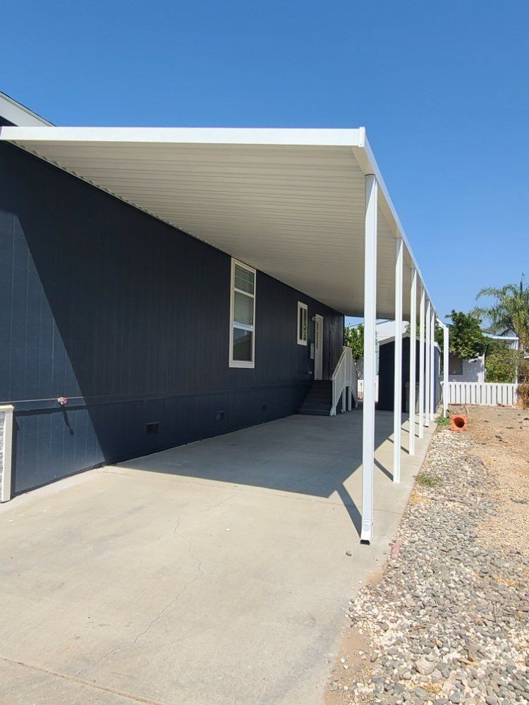 A mobile home with a white awning over the driveway.