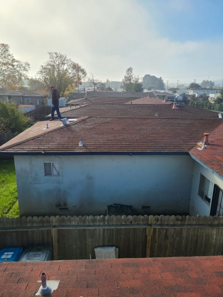 A man is standing on the roof of a house.