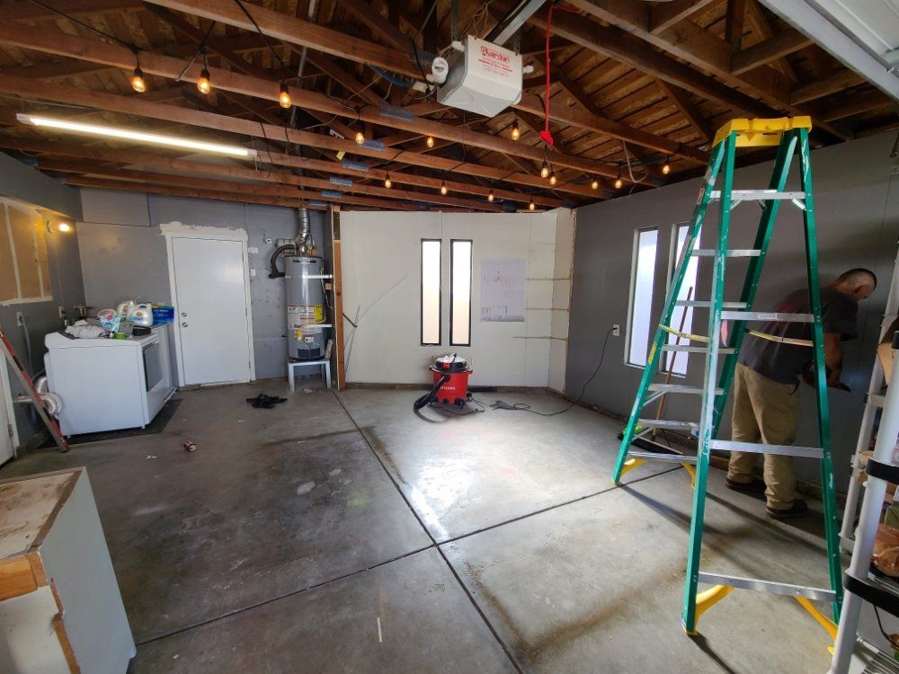 A man is standing next to a ladder in a garage.
