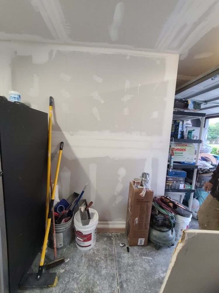 A room with a bucket of paint and a mop on the floor.