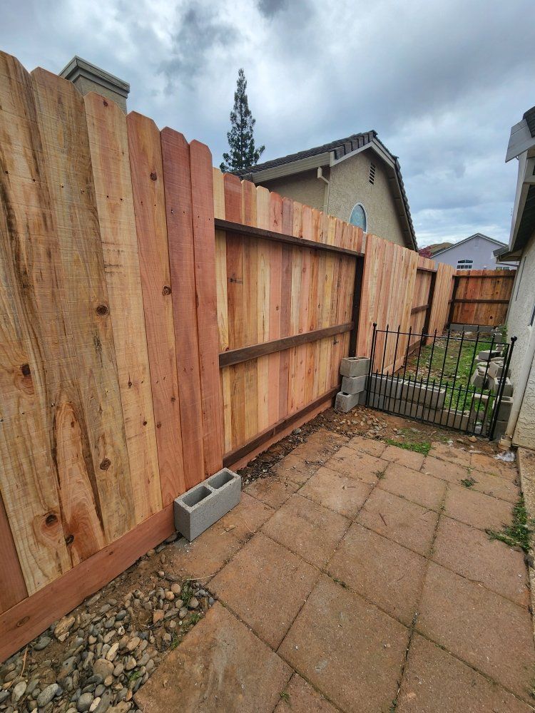 A wooden fence is sitting on top of a brick patio next to a house.