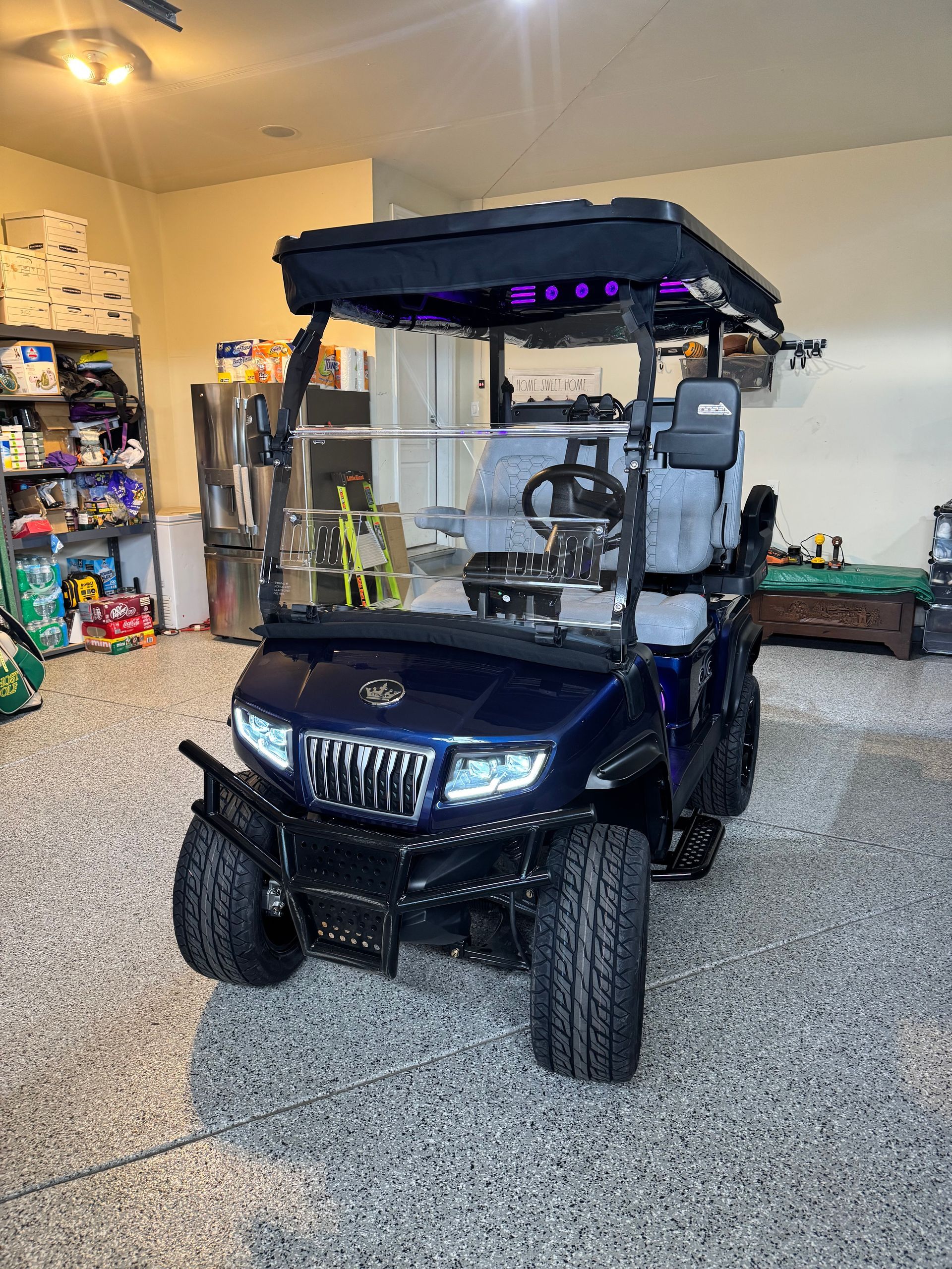 Dark blue golf cart in a garage with storage shelves and tools nearby