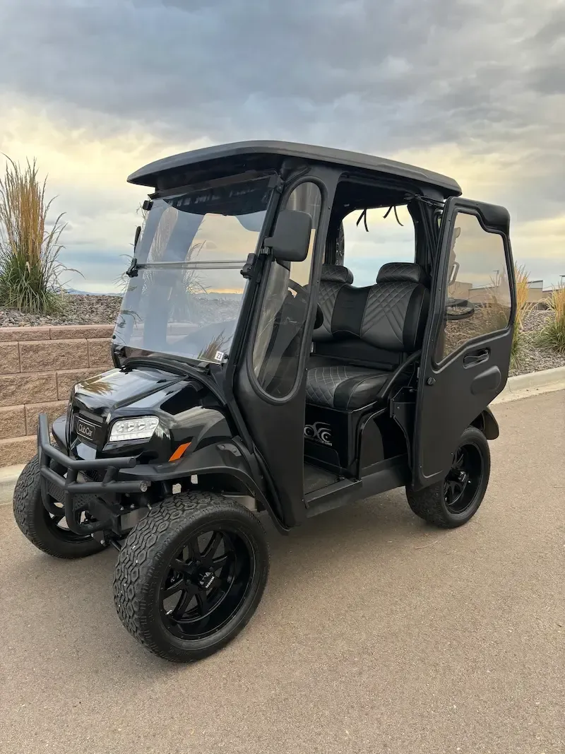 Black three-wheeled off-road vehicle parked on a road under a cloudy sky