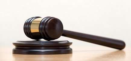 Wooden judge’s gavel resting on a round base against a light background