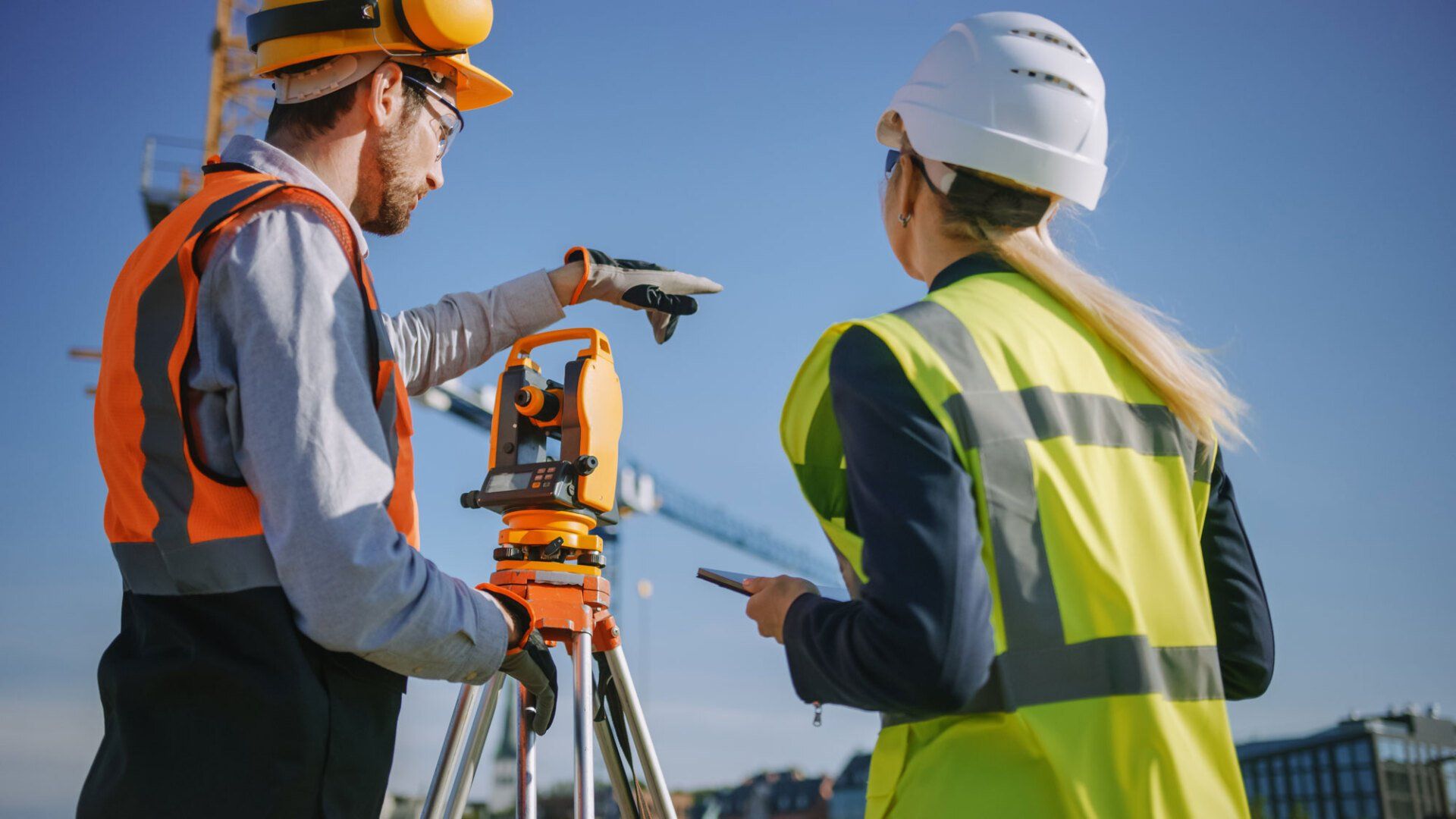 construction workers using surveying instrument for measuring angles