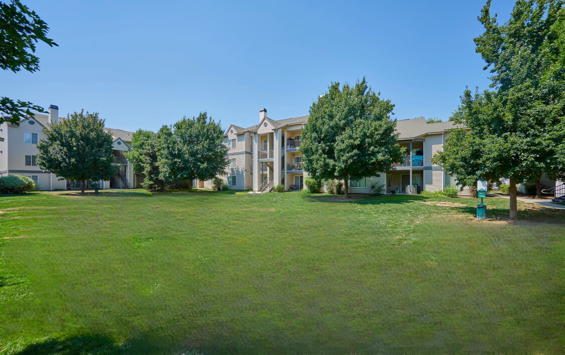 Large green lawn in front of multi-story apartment building — boise apartments for rent