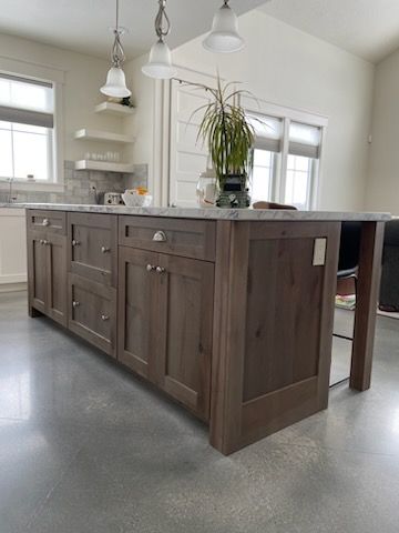 Modern kitchen with large dark wood island, marble countertop, pendant lights, and potted plant