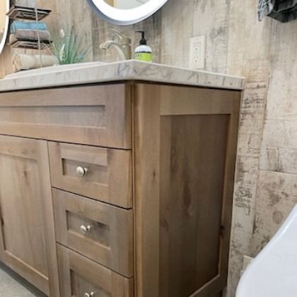 Wood bathroom vanity with light countertop, drawers, and a wall-mounted mirror in a modern bathroom.