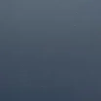 Plain gray-blue surface with faint small specks near the top center