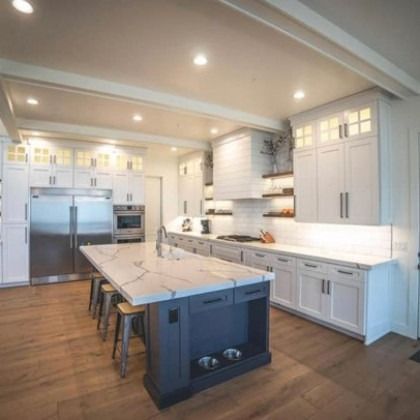 Bright modern kitchen with white cabinets, stainless appliances, and a large marble island with stools