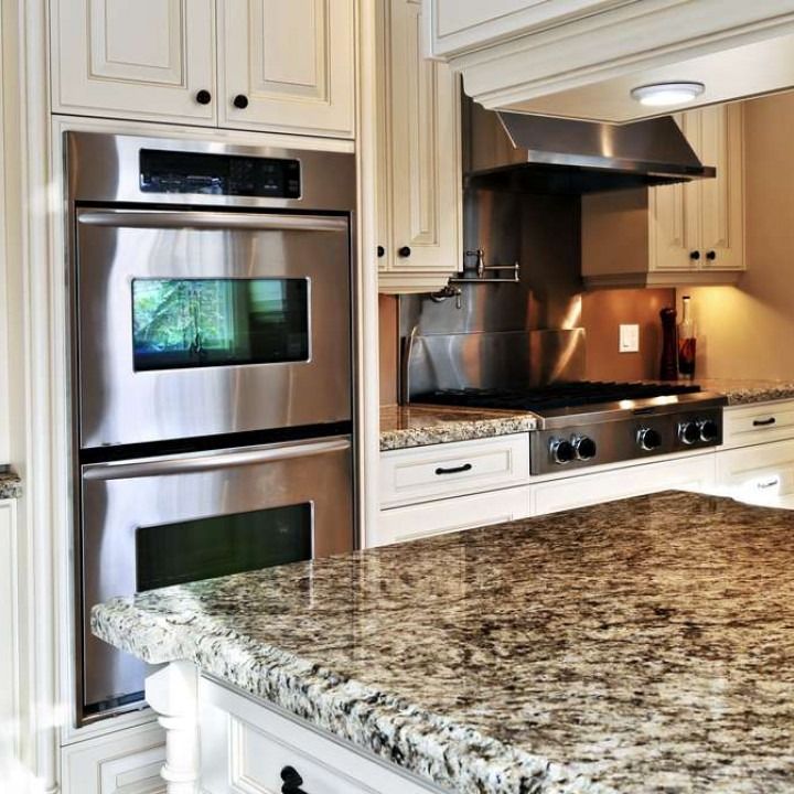 Modern kitchen with stainless steel appliances, granite island countertop, and cream cabinets