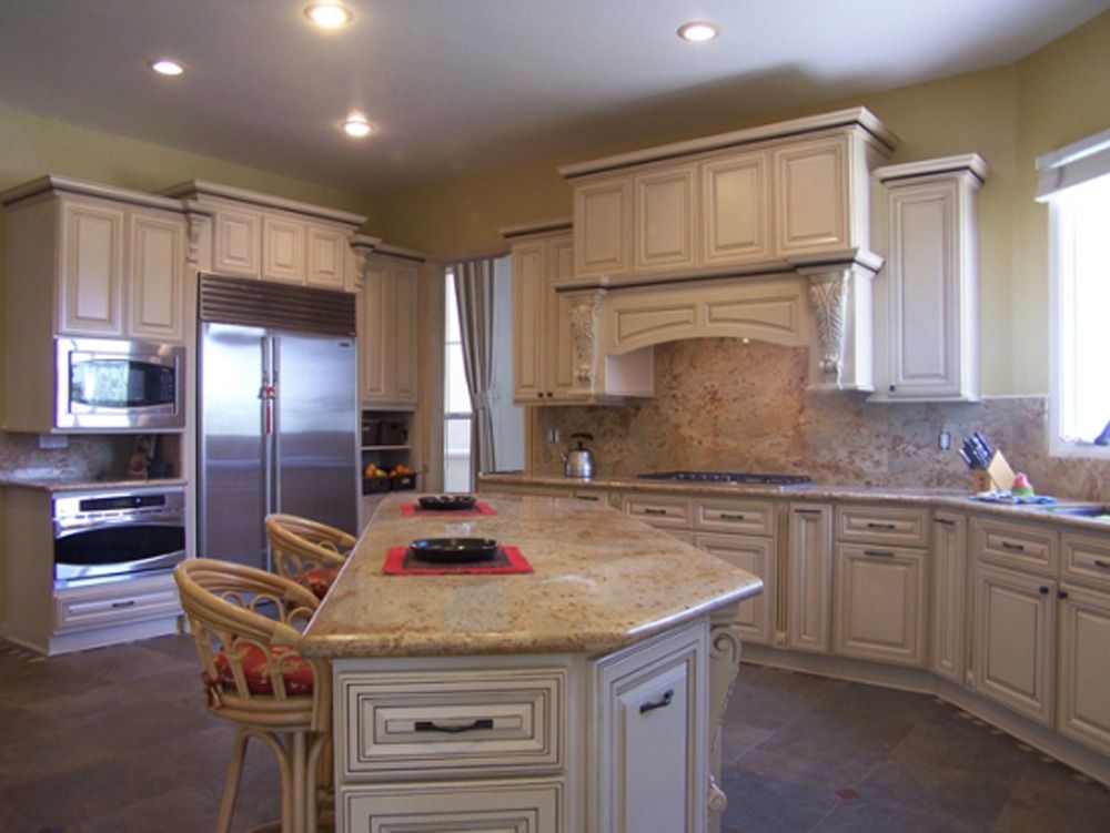 Spacious beige kitchen with island, stainless steel appliances, and tiled backsplash