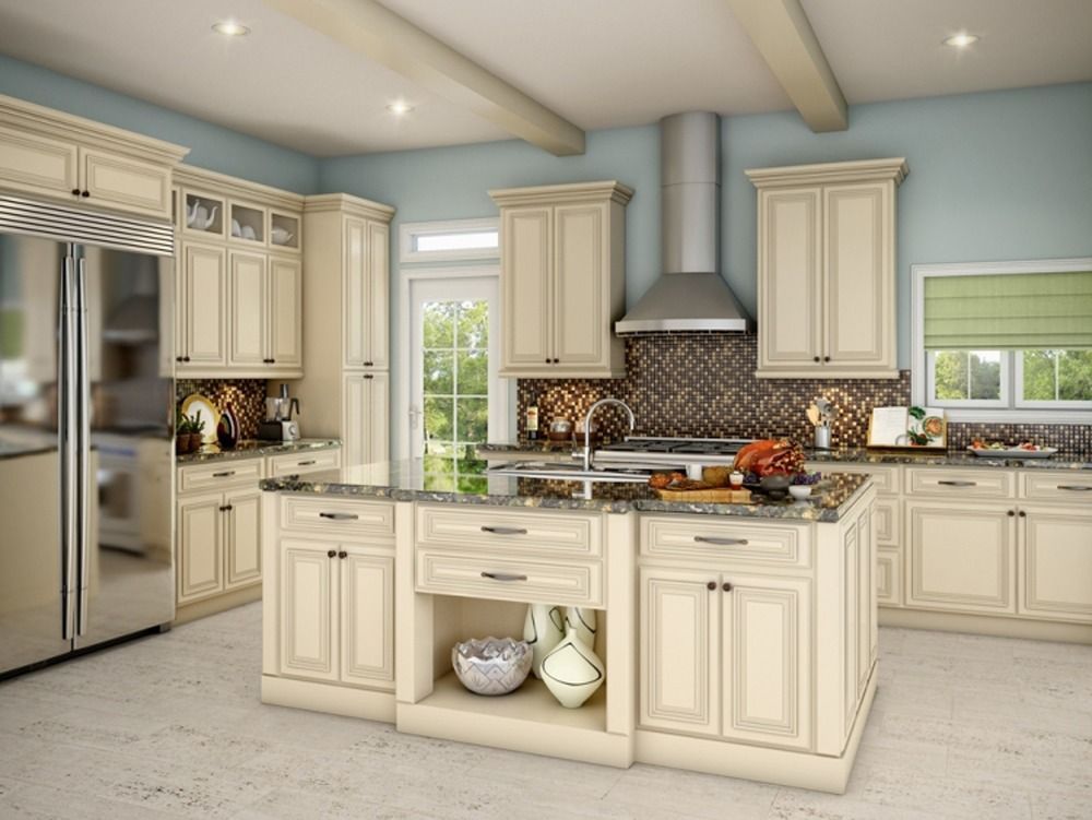 Bright cream kitchen with stainless fridge, island, and mosaic backsplash in a sunlit home.