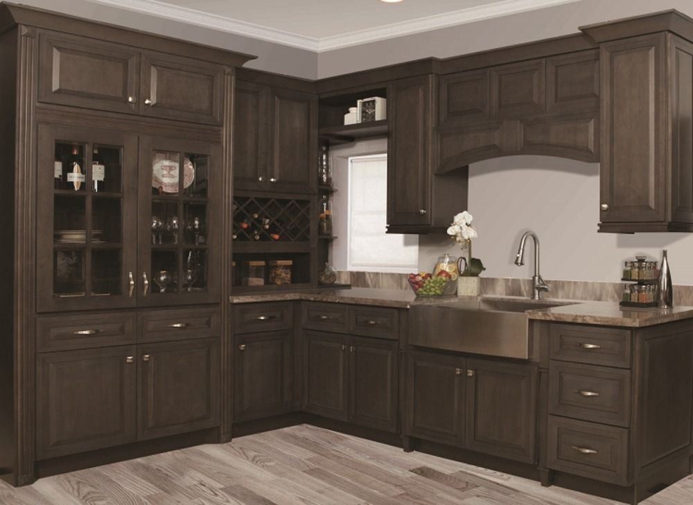 Dark wood kitchen with cabinets, wine rack, sink, and light countertop against pale walls.