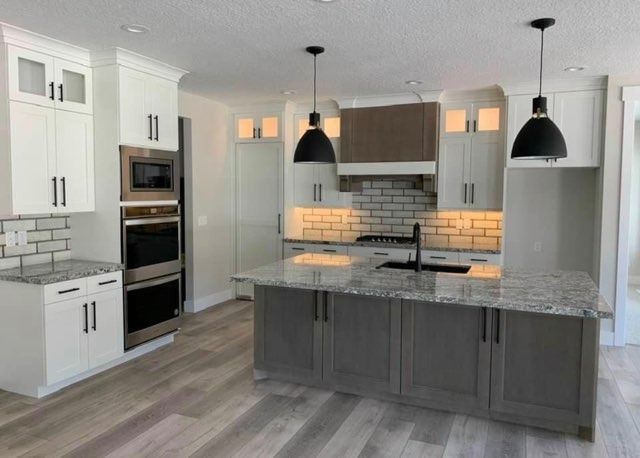 Modern gray kitchen with island, pendant lights, white cabinets, and tiled backsplash