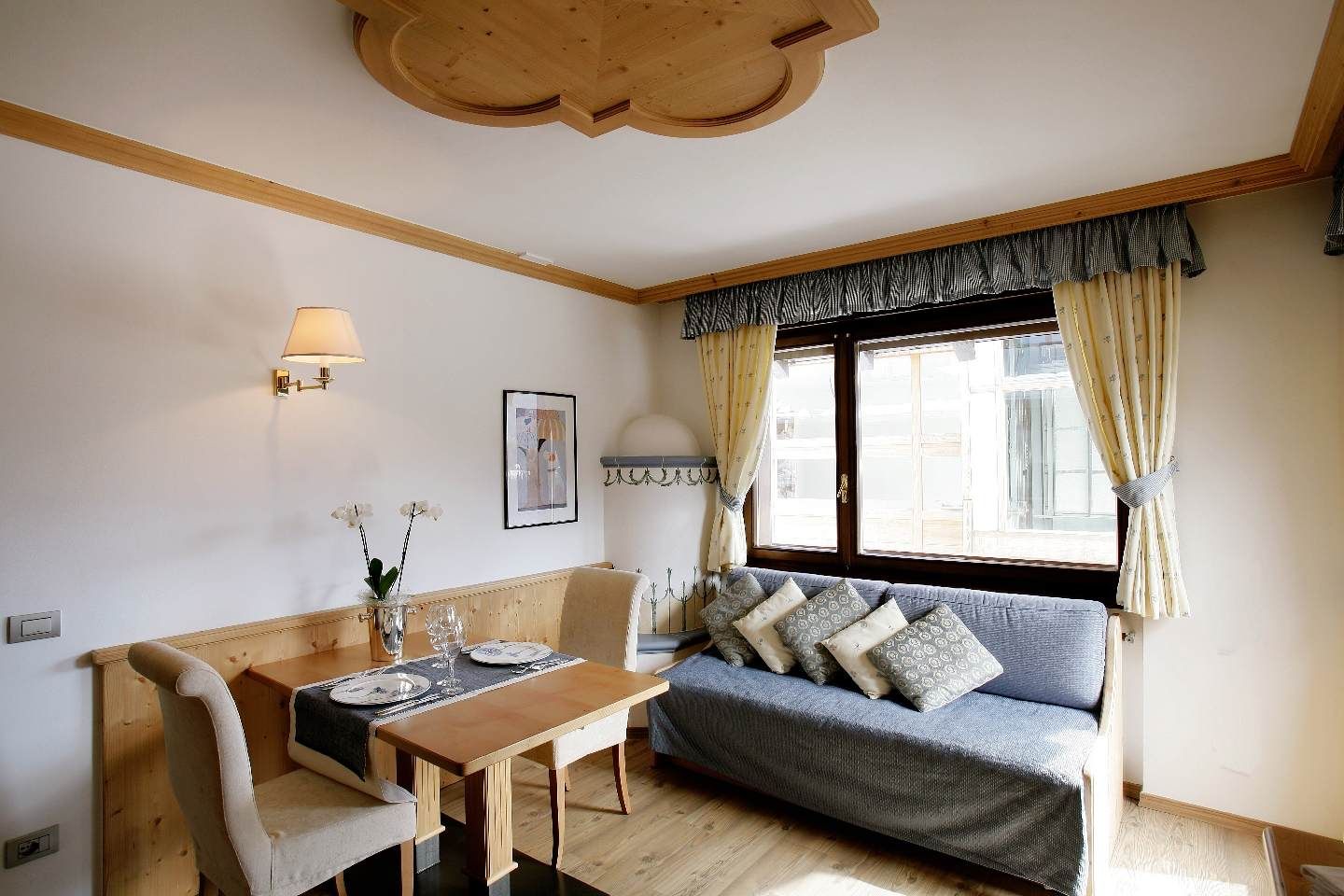 Cozy living-dining room with sofa, table, wall lamp, and window with curtains