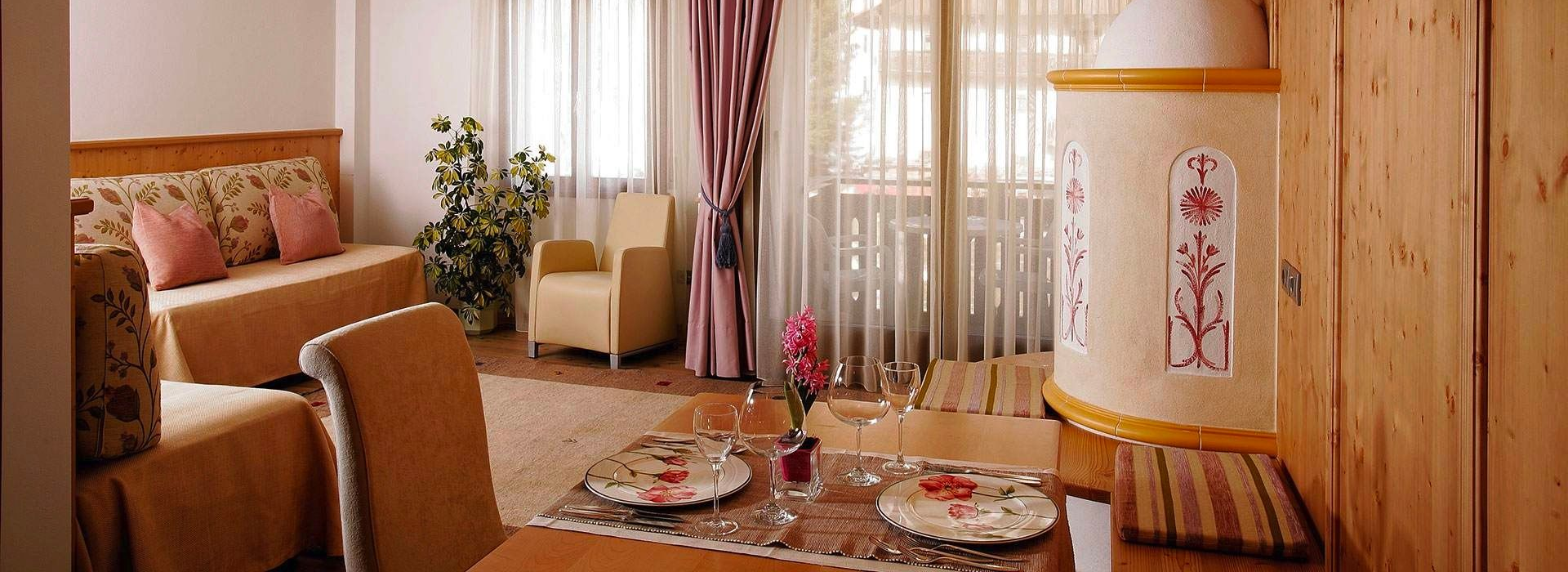 Cozy living room with sofa, woven chair, round rug, plants, and sheer curtains in warm wood tones