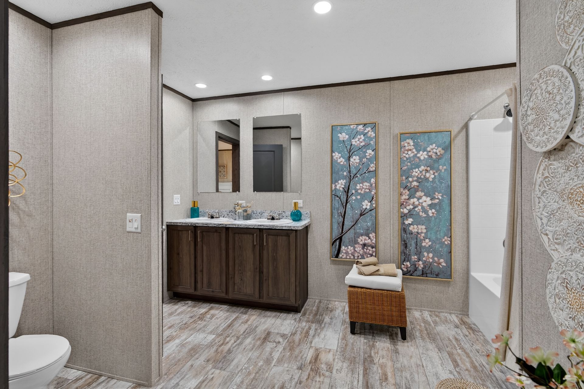 Modern bathroom vanity with double sinks, patterned wall art, and a stool in a gray-tiled room