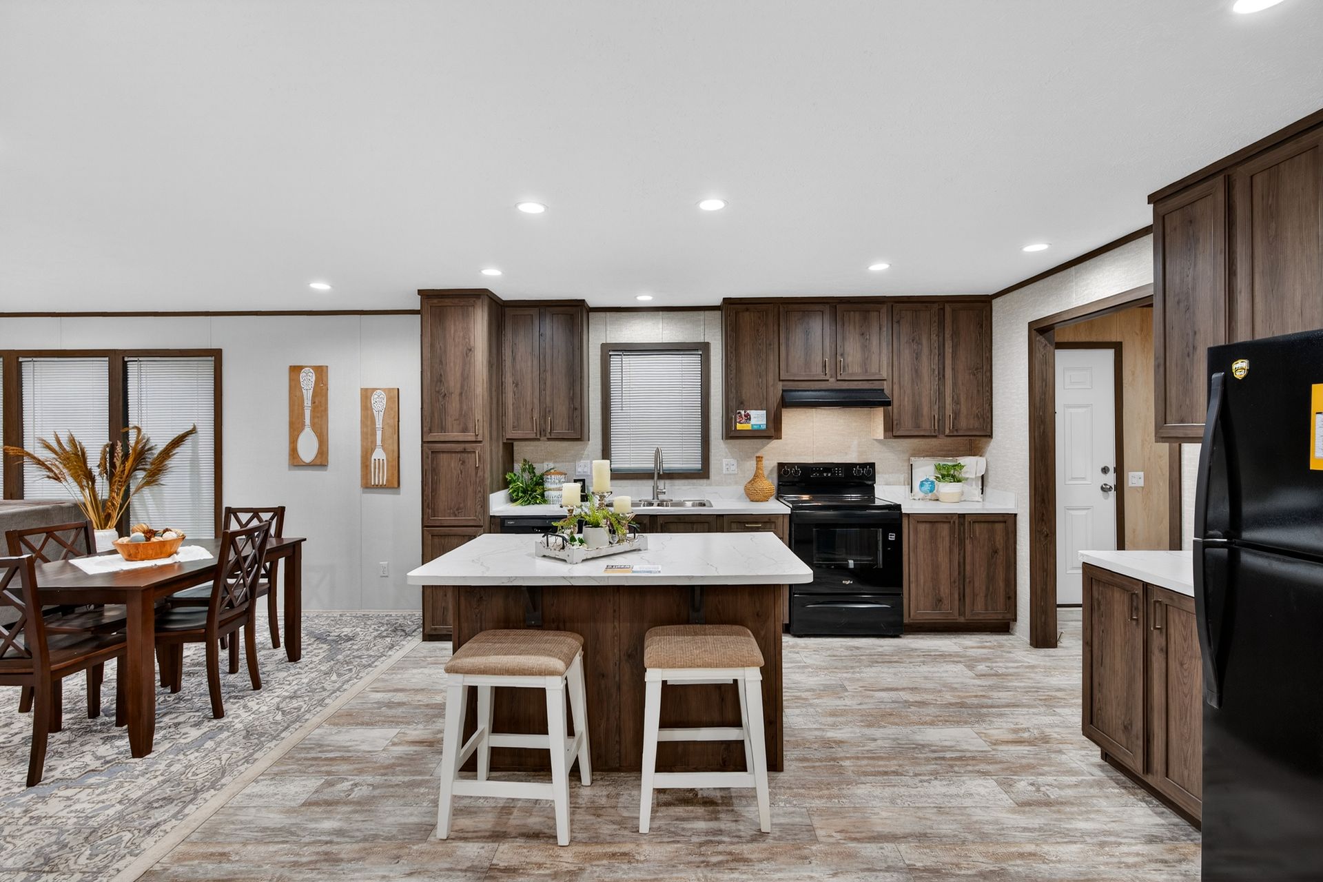 Modern kitchen and dining area with island, white stools, wood cabinets, and stainless steel appliances