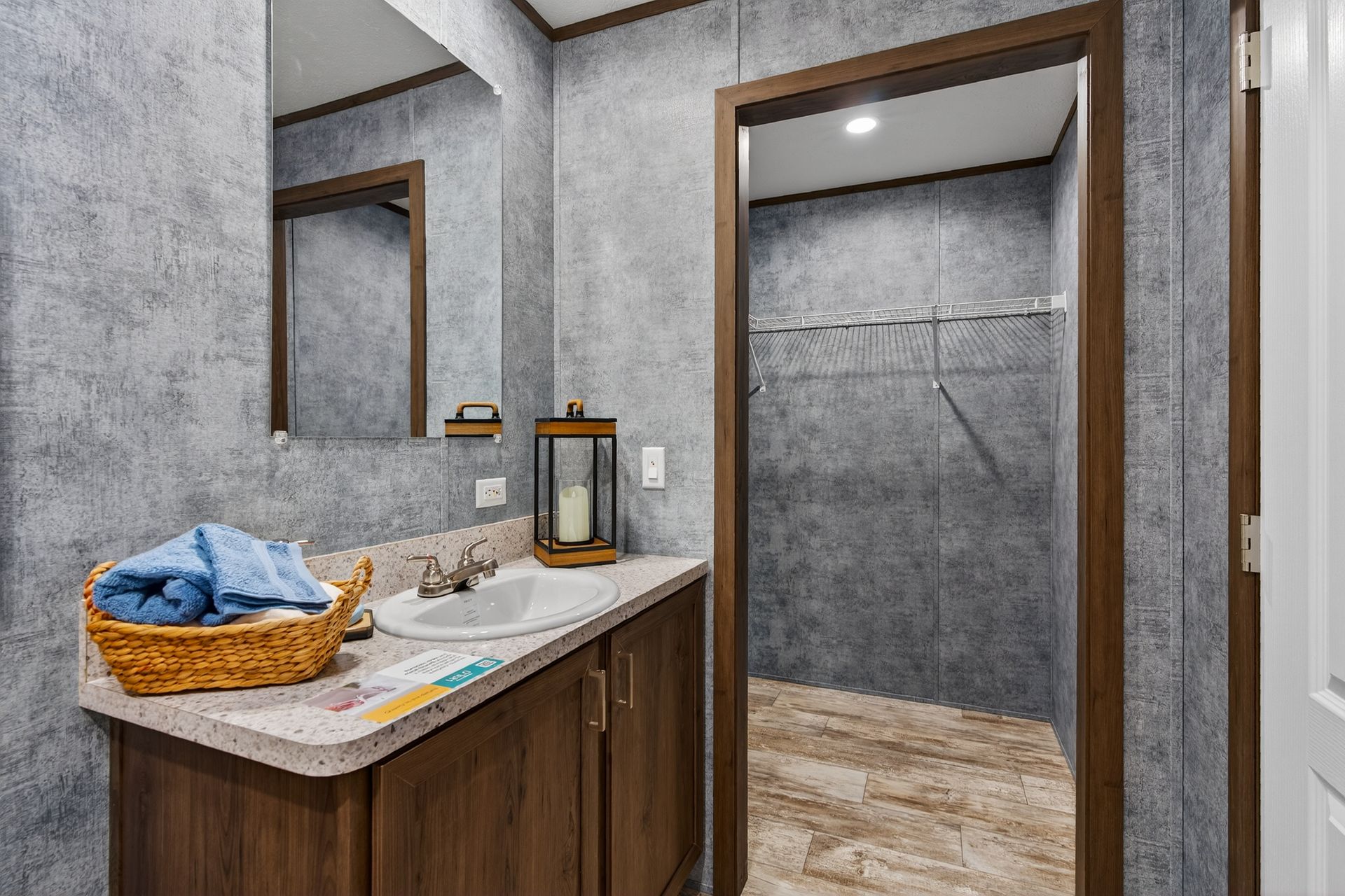 Modern bathroom vanity with wood cabinet, marble countertop, mirror, basket, and open walk-in shower room.
