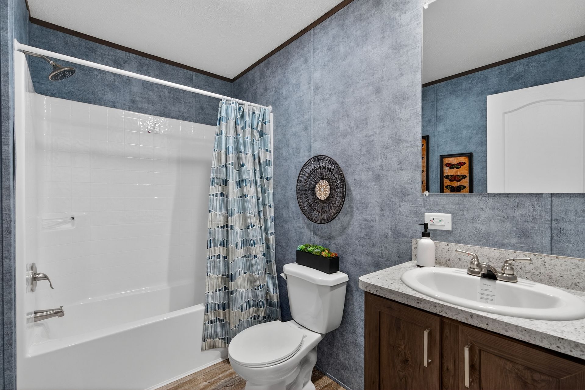 Modern bathroom with a tub, toilet, sink, and blue-gray walls