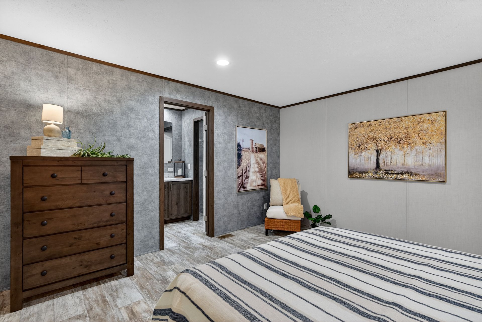 Bedroom with striped bedspread, dresser, chair, wall art, and an open doorway to a hallway