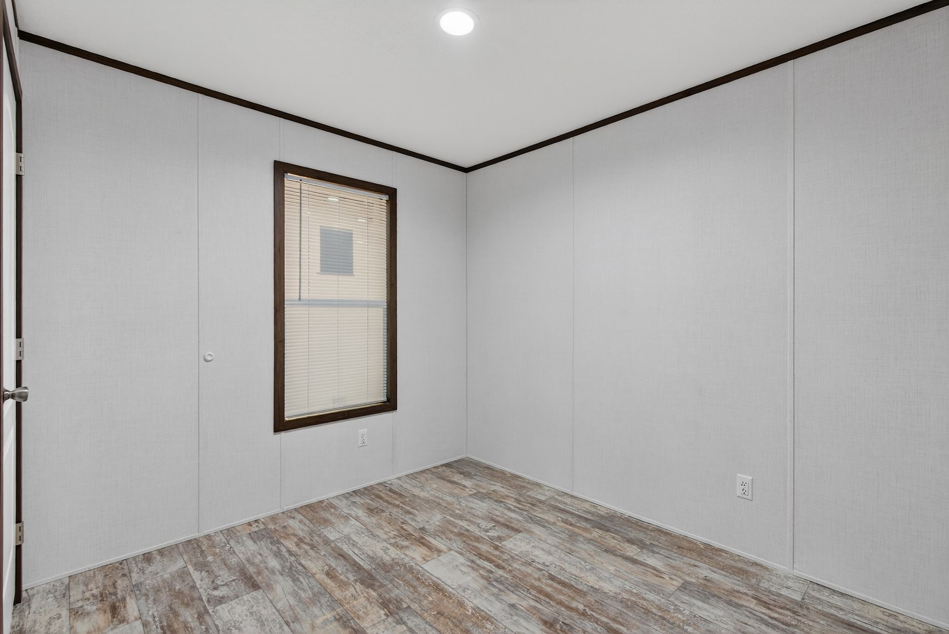 Empty gray room with wood-look floor, white walls, and a single framed window covering.