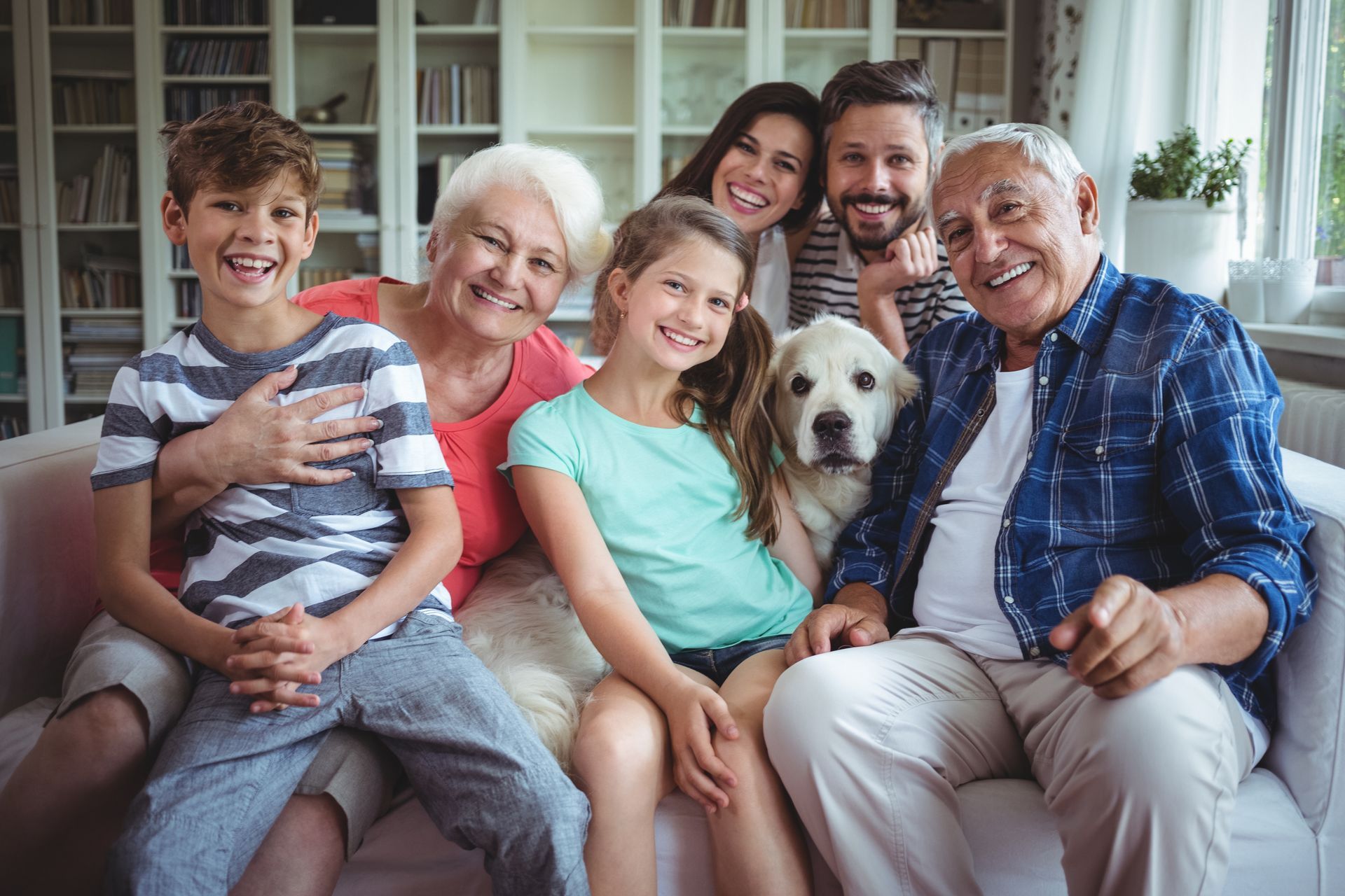 Smiling family seated on a sofa with a dog in a bright living room