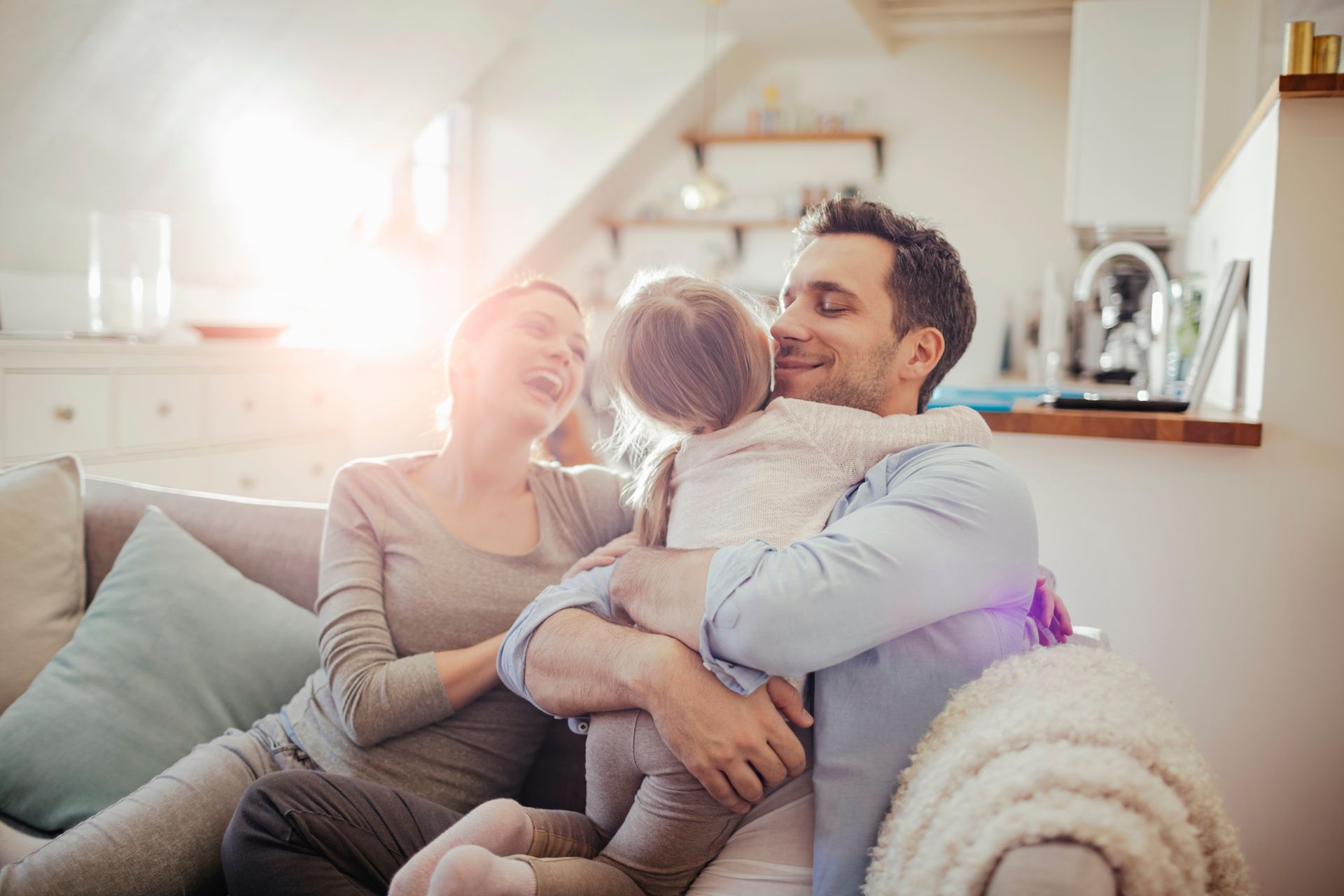 Family sitting on a couch, smiling and hugging in a bright living room