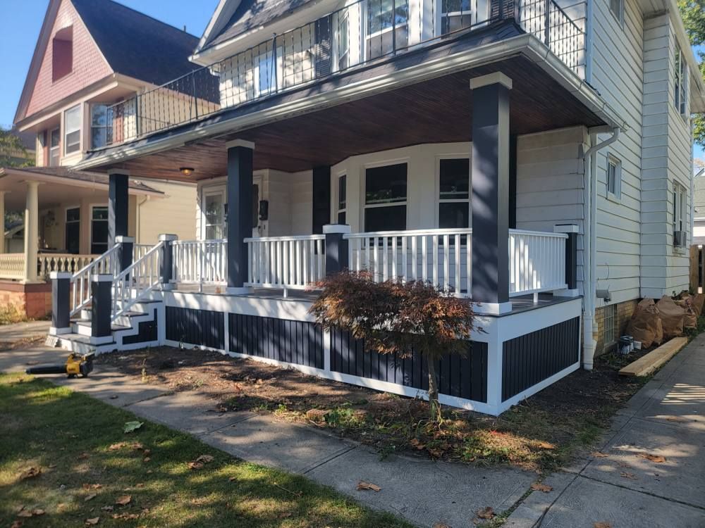 A wooden deck with stairs and a bench in the backyard of a house.