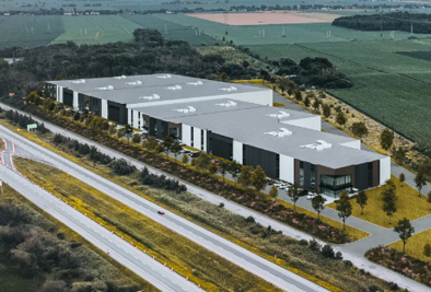 Vue aérienne d'un complexe industriel moderne à côté d'une autoroute, entouré de champs.